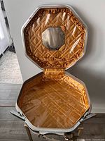 Open case showing gold quilted satin interior, clear vinyl lining, mirror and pockets