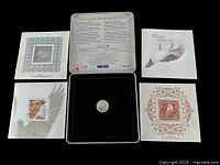 Full contents laid out: tin lid with certificate, four souvenir sheets, medallion in tray