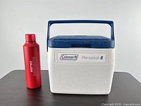 Front view of Coleman Personal 8 cooler and red insulated bottle