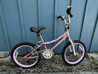 Left side view of pink and silver Movelo kids bike showing frame, wheels, chainring, kickstand