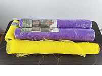 Three full rolls and one partial roll of purple and yellow mesh ribbon on table