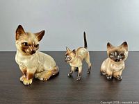 Front view of three porcelain Siamese cat figurines
