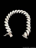 Full view of sterling silver curb link bracelet in semi-closed position