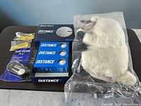 All items grouped on table: golf balls box open showing three sleeves, packaged Top-Flite G-Tool, plush headcover in bag, two packs yellow tees