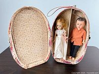 Open red white blue oval wardrobe case showing two vintage Vogue dolls inside
