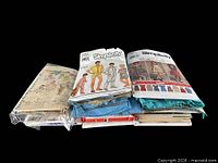 Stack of vintage sewing patterns and blue fabric bundles
