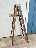 Front angled view of wooden folding ladder showing A-frame and metal top cap