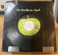 Record in black Apple company sleeve showing front label through center cutout