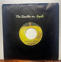 Front view showing record in black Apple company sleeve