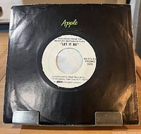 Record in black Apple sleeve showing white label side with printed details