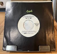 Record in black Apple sleeve showing A-side label