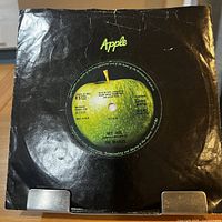 Front view of record in black Apple sleeve showing green apple label through die-cut