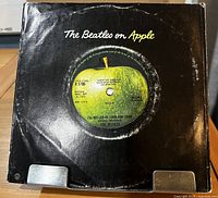 Front view of black Apple company sleeve with record inside