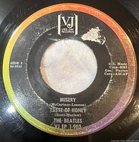 Side 1 label showing Misery / Taste Of Honey, rainbow brackets logo, label tear visible