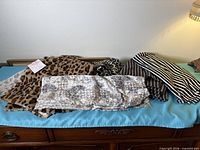 Grouped fabrics laid out on blue surface: leopard faux fur, leopard cotton, abstract print, two striped fabrics