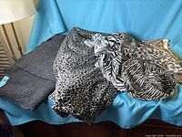 Overview of four folded animal print fabrics on blue backdrop