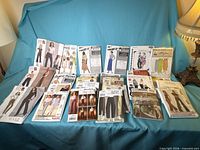 Full lot of roughly 20 sewing pattern envelopes displayed on a sofa