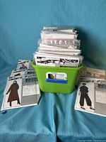 Green bin filled with numerous sewing patterns, several patterns laid out in front
