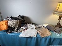 Tabletop view of basket with pile of assorted fabric pieces and lamp for scale