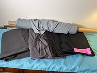 Bolt of light grey fabric and folded black/grey fabrics on surface