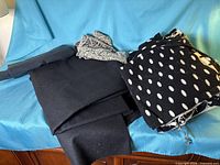 All three fabric pieces draped: two solid black, one black with white polka dots and additional lace motif piece