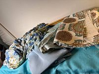 Overview of three folded fabric pieces: abstract print, medallion pattern, solid light blue