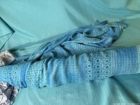 Turquoise patterned fabric rolled on turquoise background