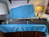 Three rolled fabric bolts on cabinet, blue drape background