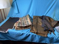 Group view of three different bronze fabrics folded on chair