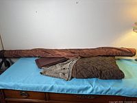 Bolt of copper fabric with additional brown and grey fabrics folded below