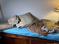 Overall view of the pile of folded brown and taupe fabrics on a blue surface