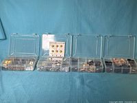 Four plastic compartment boxes open showing assorted buttons