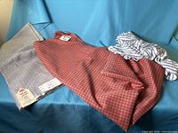 All three fabric pieces displayed: grey check folded, red check draped, white striped bundled