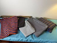 Five folded pieces of striped fabric on surface