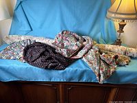 Overall view of five floral fabrics on sofa, showing bolt and folded pieces