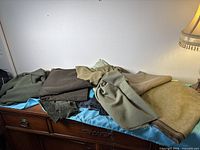 Stack of assorted green fabric pieces on dresser