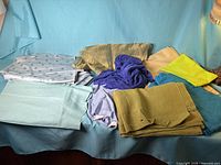 Group of assorted green and blue fabric pieces on couch
