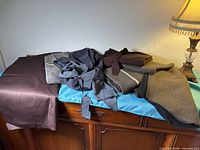 Assorted folded grey and brown fabrics on cabinet, view of variety