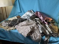 Pile of assorted metallic and other fabric remnants on blue backdrop
