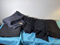 Five folded pieces of black/charcoal fabric on table