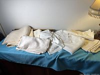Full grouping of folded white and beige fabrics on table