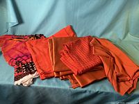 Stack of six orange and coral fabric pieces showing variety of textures