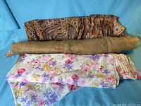 Three fabric bolts showing patterns: paisley, tulle, floral
