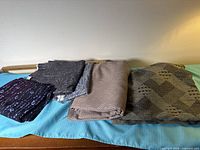 Five folded fabric pieces on turquoise cloth