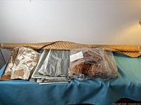 Overall view: pillow trim bag, bolt of gold fabric, four folded fabric samples on table