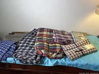 Seven folded plaid fabrics displayed on dresser