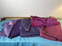 Five stacked purple fabric pieces displayed on table