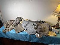 Pile of assorted silver, gold and grey fabrics on table