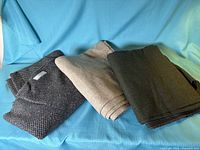 Three folded pieces of tweed fabric on blue backdrop