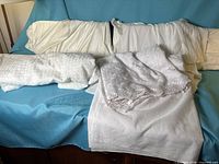 All three white fabric pieces displayed on bed